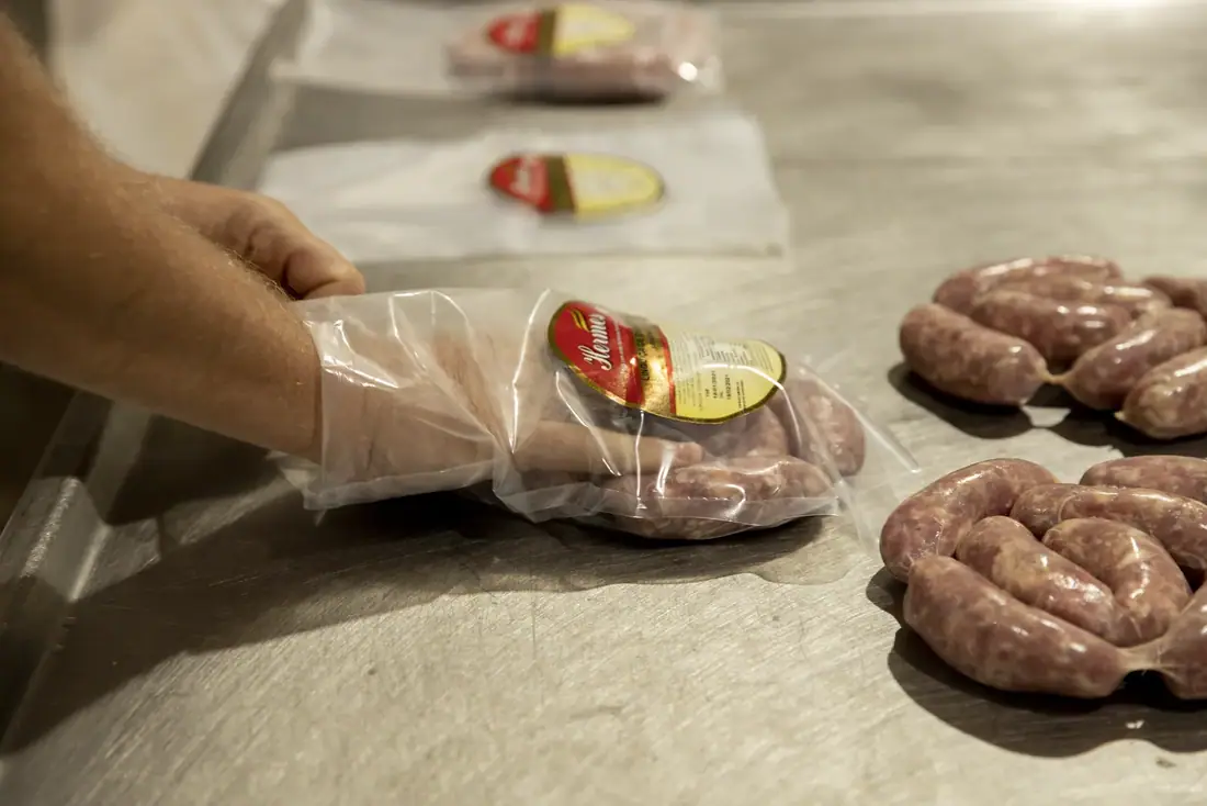 Embalagem e rotulagem de linguiça na mesa de produção
