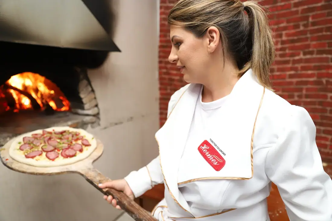Pizza sendo levada ao forno a lenha na Casa Colonial Hermes