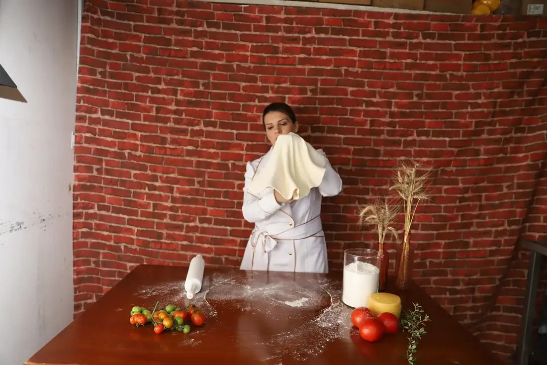 Massa de pizza sendo aberta à mão