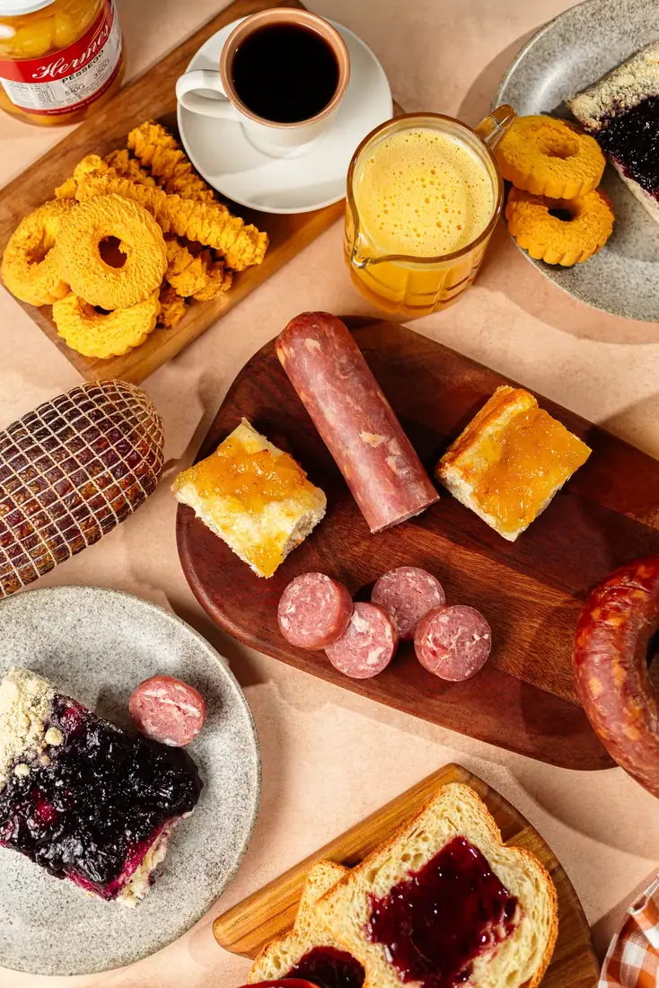 Mesa colonial posta com salame, pão, cuca de frutas vermelhas, biscoitos e café